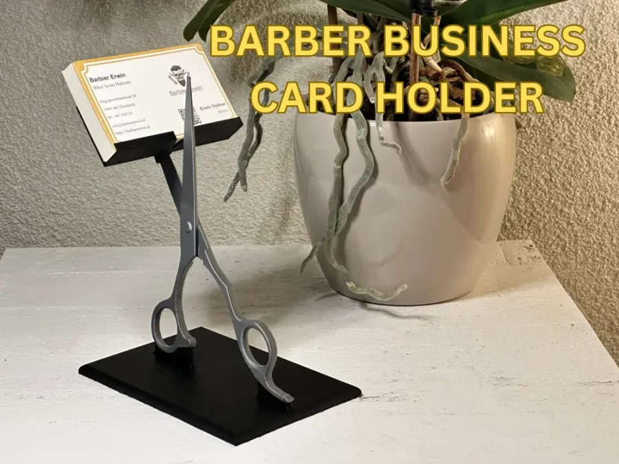 Visittkortholder for frisør og barberer med sølvgrå saksfigur, sort kortstøtte og rektangulær sort fot med visittkort øverst.