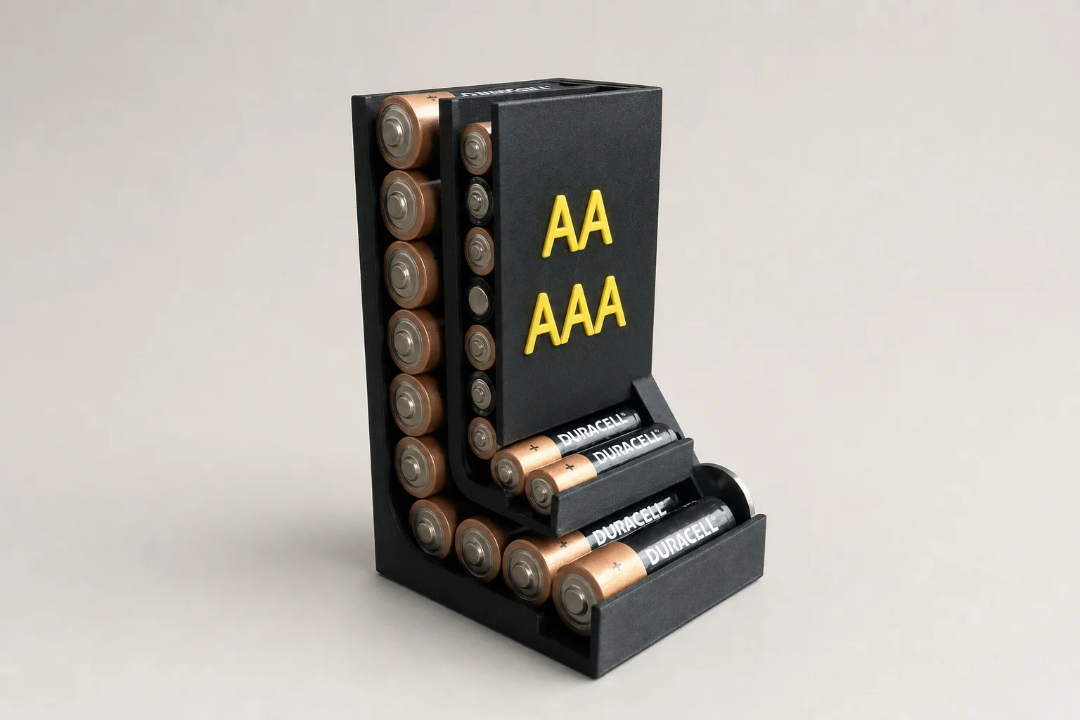 Mørk stående batteriholder fylt med AA- og AAA-batterier, med åpne sidespor, trinnvis front og tydelig gul AA/AAA-merking.